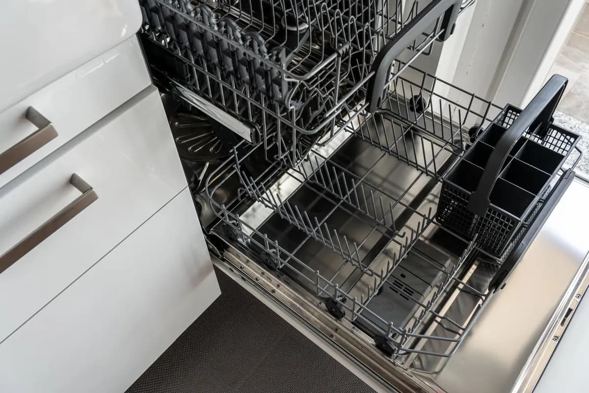 Open stainless steel dishwasher with empty racks